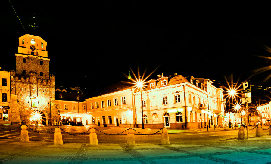 Nocny widok z daleka na Bramę Krakowską i Tinto Wine Bar zdjęcie do galerii